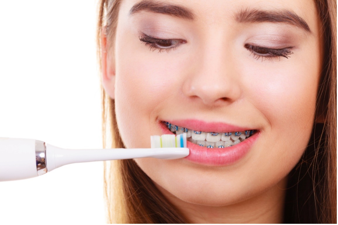 girl with braces looking at electric toothbrush