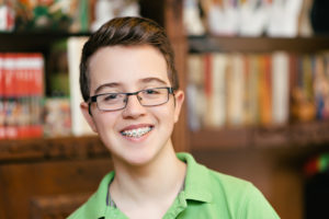 Happy teenage boy with braces and glasses, smiling