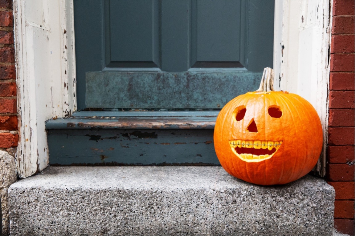 A carved pumpkin with braces on a porch