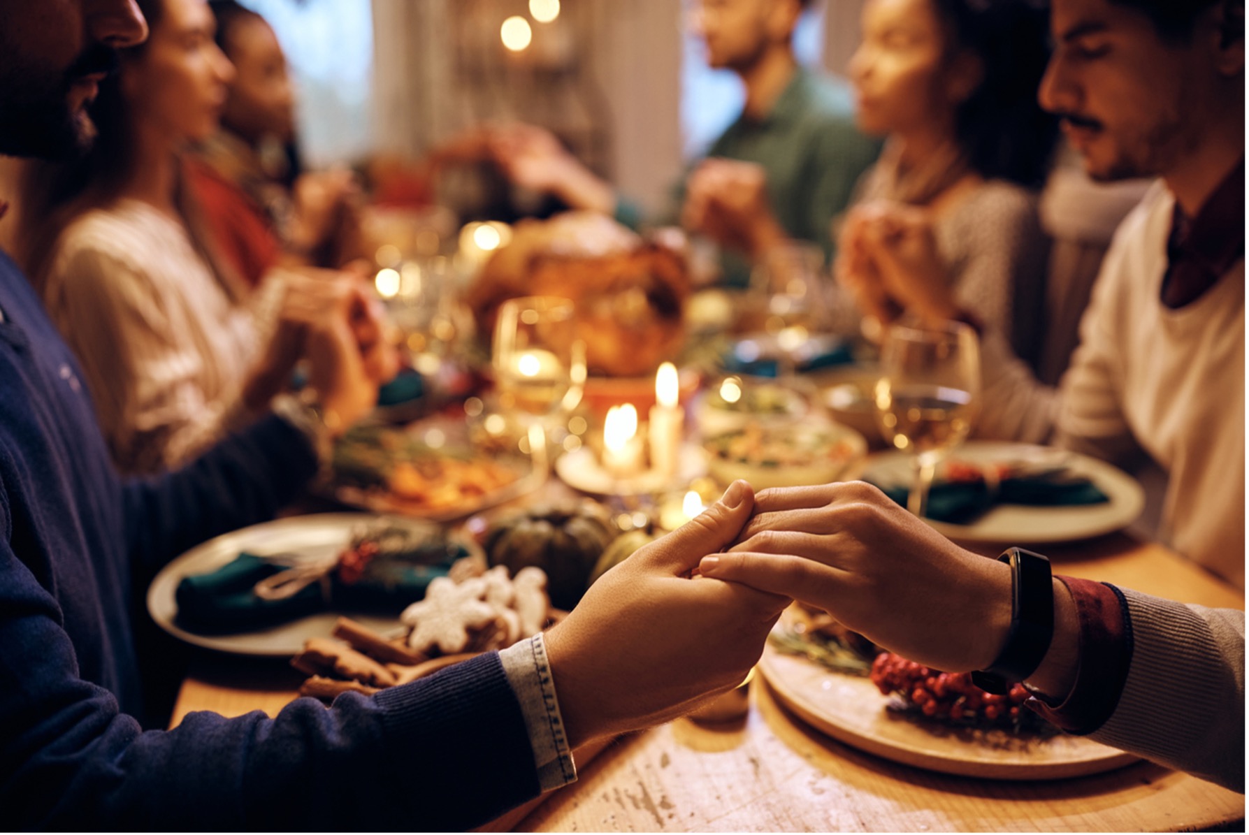 A group of people sitting around a thanksgiving table with food and candles
