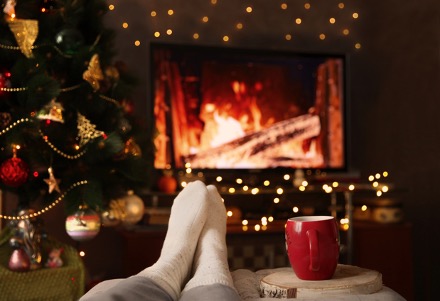 A person's feet in front of a fire place surrounded by Christmas decorations