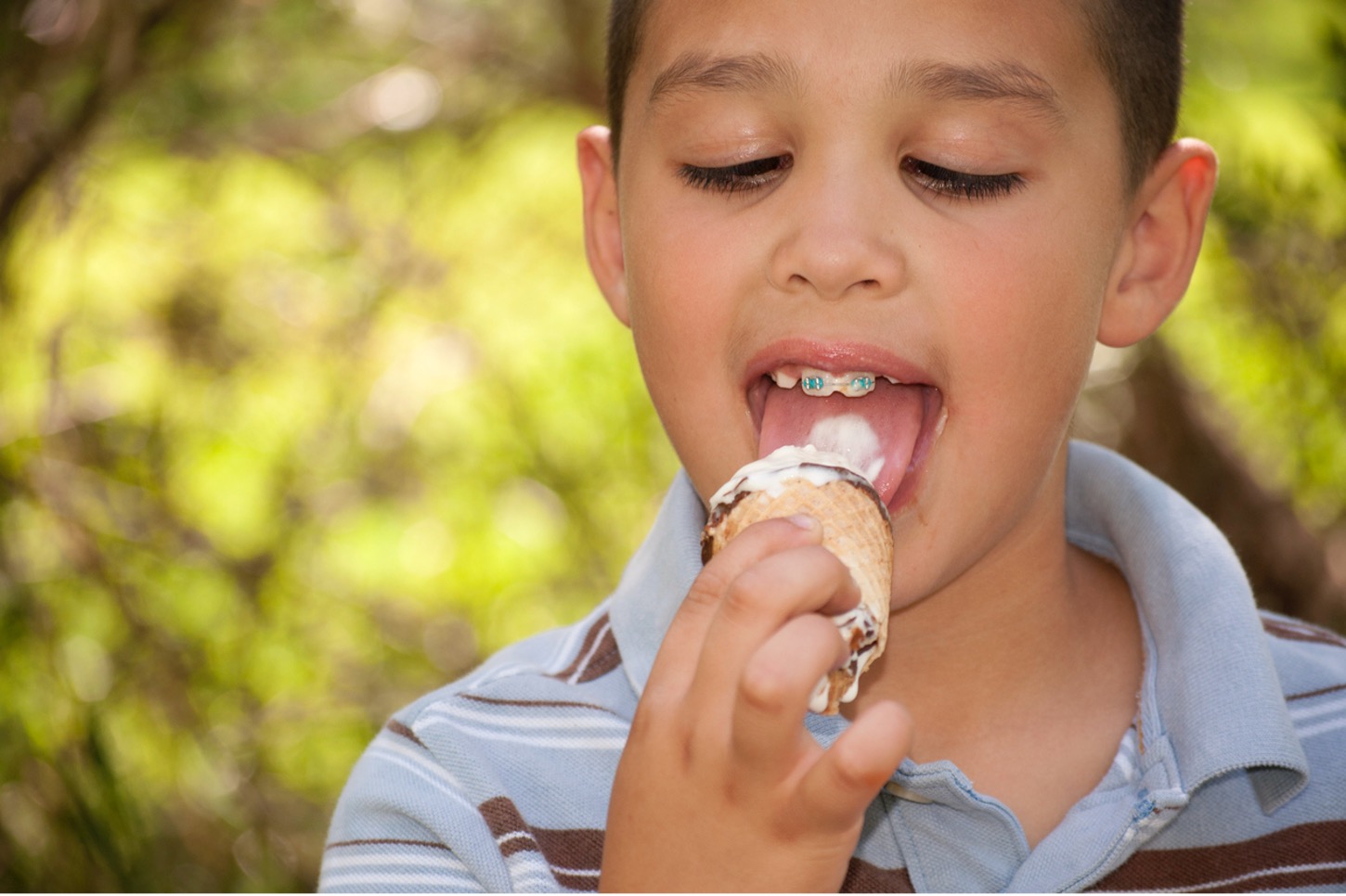 A young person with braces eating an ice cream cone