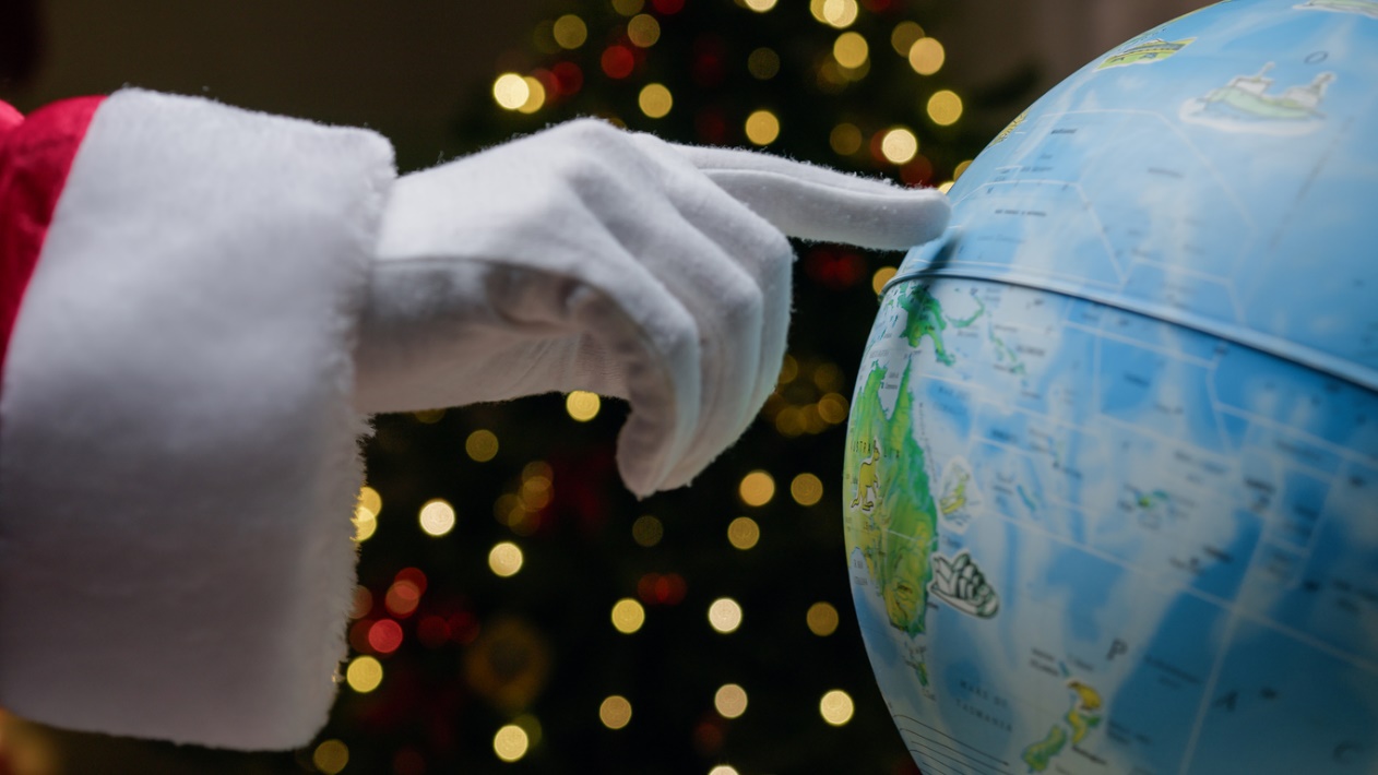 A person pointing at a globe, Holiday Braces Tips: Smiling Through Global Holiday Traditions