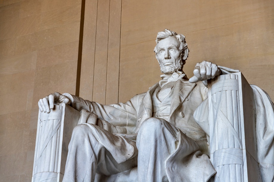 A statue of a Abraham Lincoln sitting in a chair at the Lincoln Memorial