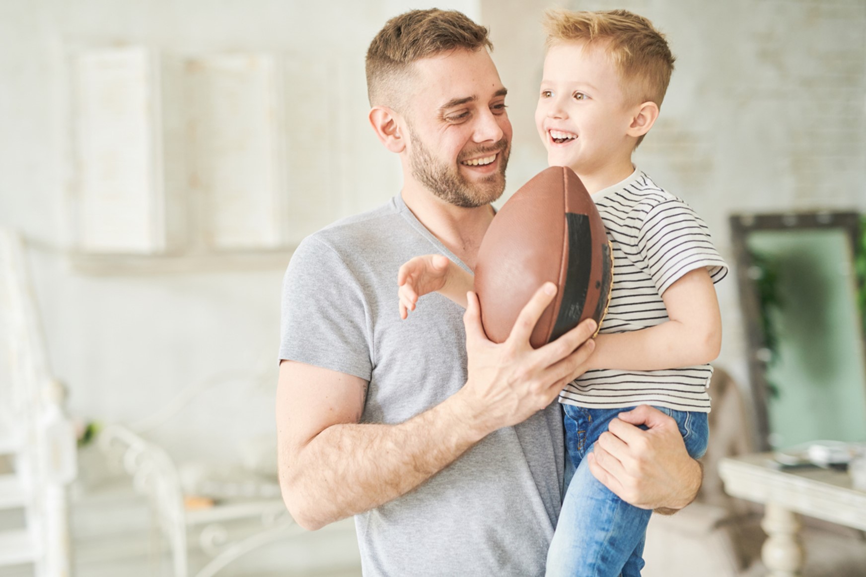 A person holding a child and a football, Get Your Smile Game On with Children's Orthodontic Care!