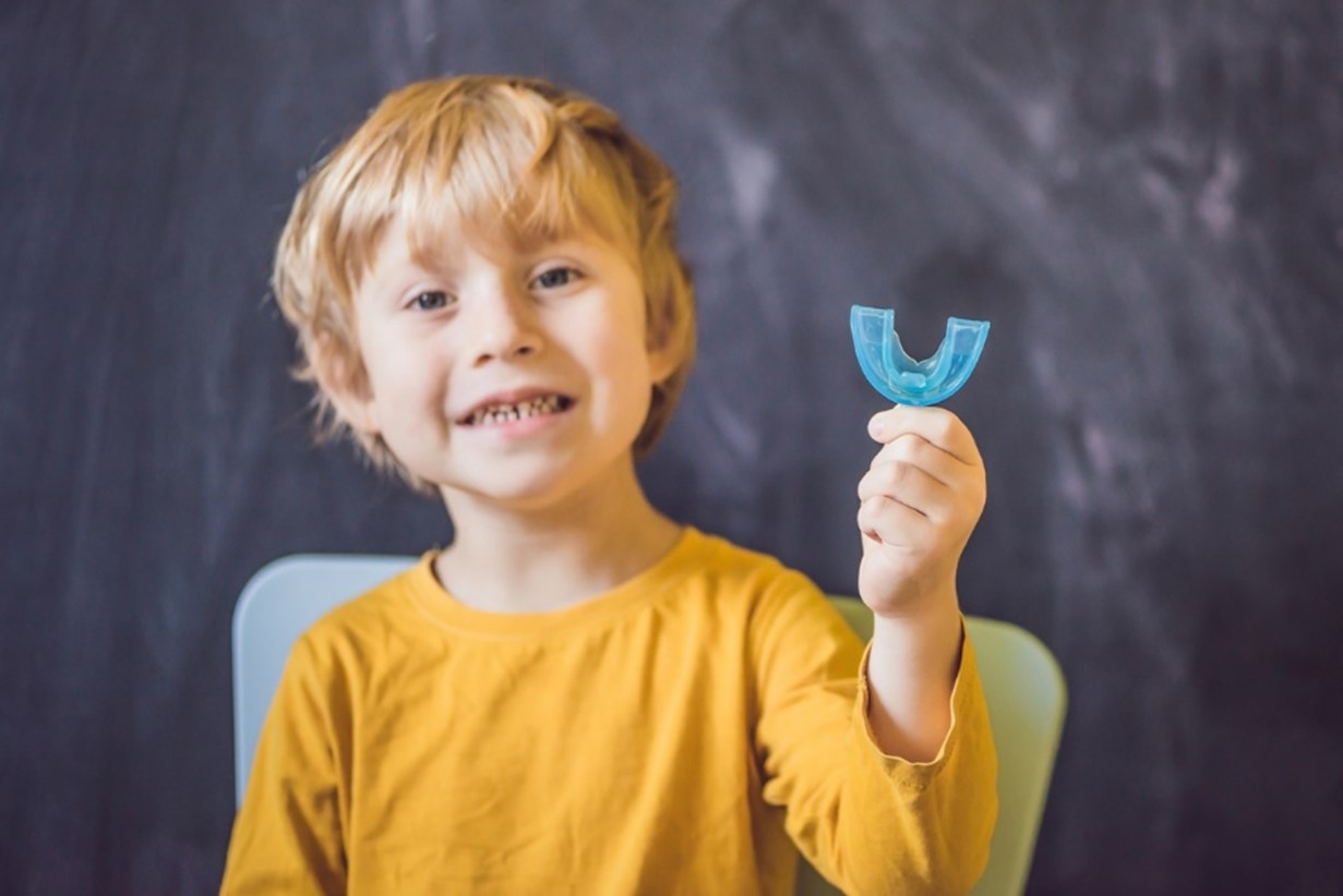 Spacing for Incoming Teeth, A child holding a blue mouthguard