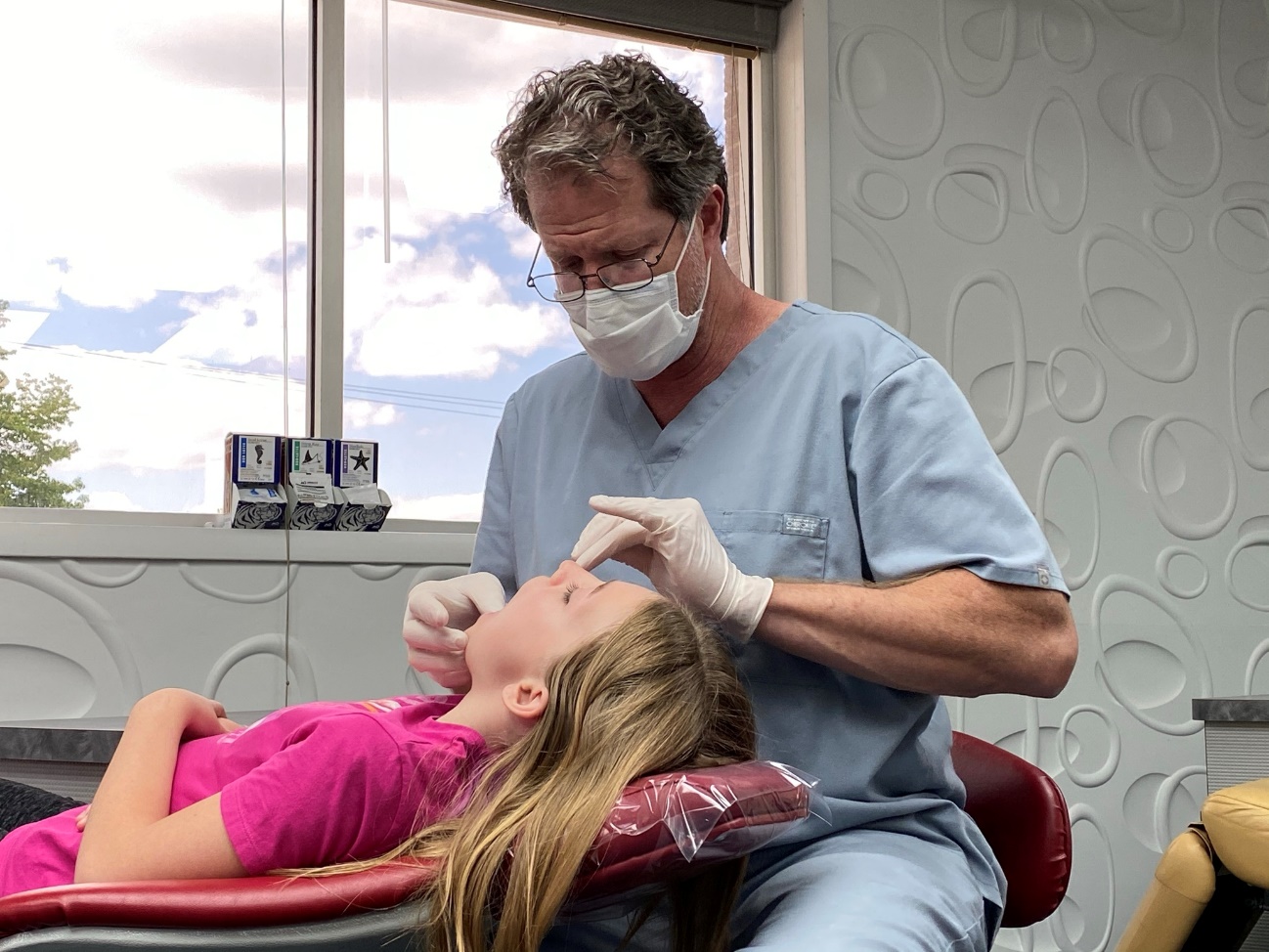 signs your child may need braces, A dentist looking at a girls teeth