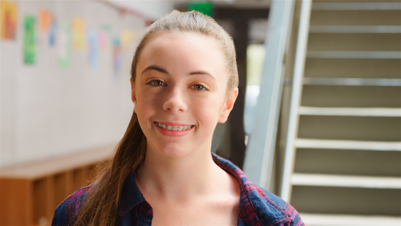 Smiling teenage girl wearing braces at school.